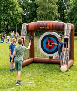 Drie jongens die spelen met het opblaasbare bijlwerpspel met klittenband bijltjes in de tuin.
