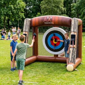 Drie jongens die spelen met het opblaasbare bijlwerpspel met klittenband bijltjes in de tuin.